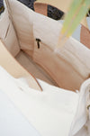Close-up of a beige handbag with a zipper pocket.