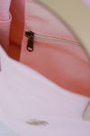 Close-up of a pink bag with a gold zipper.